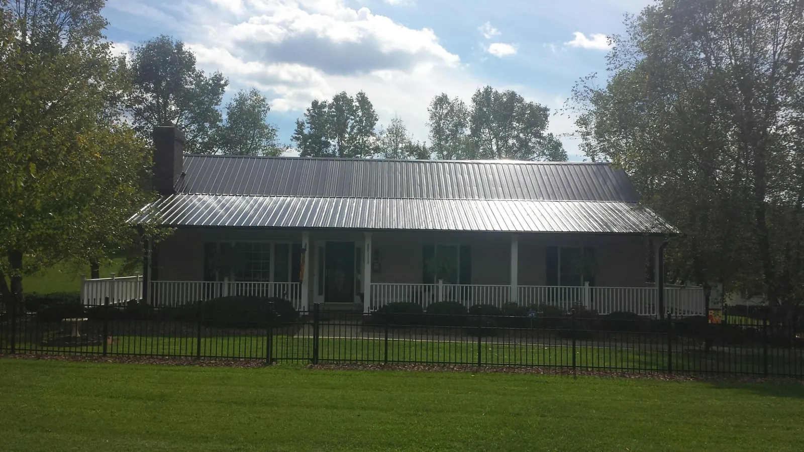 Gray metal roof on a brick ranch with a full width front porch — Gutter Guard Installation work by our crew in Hamilton